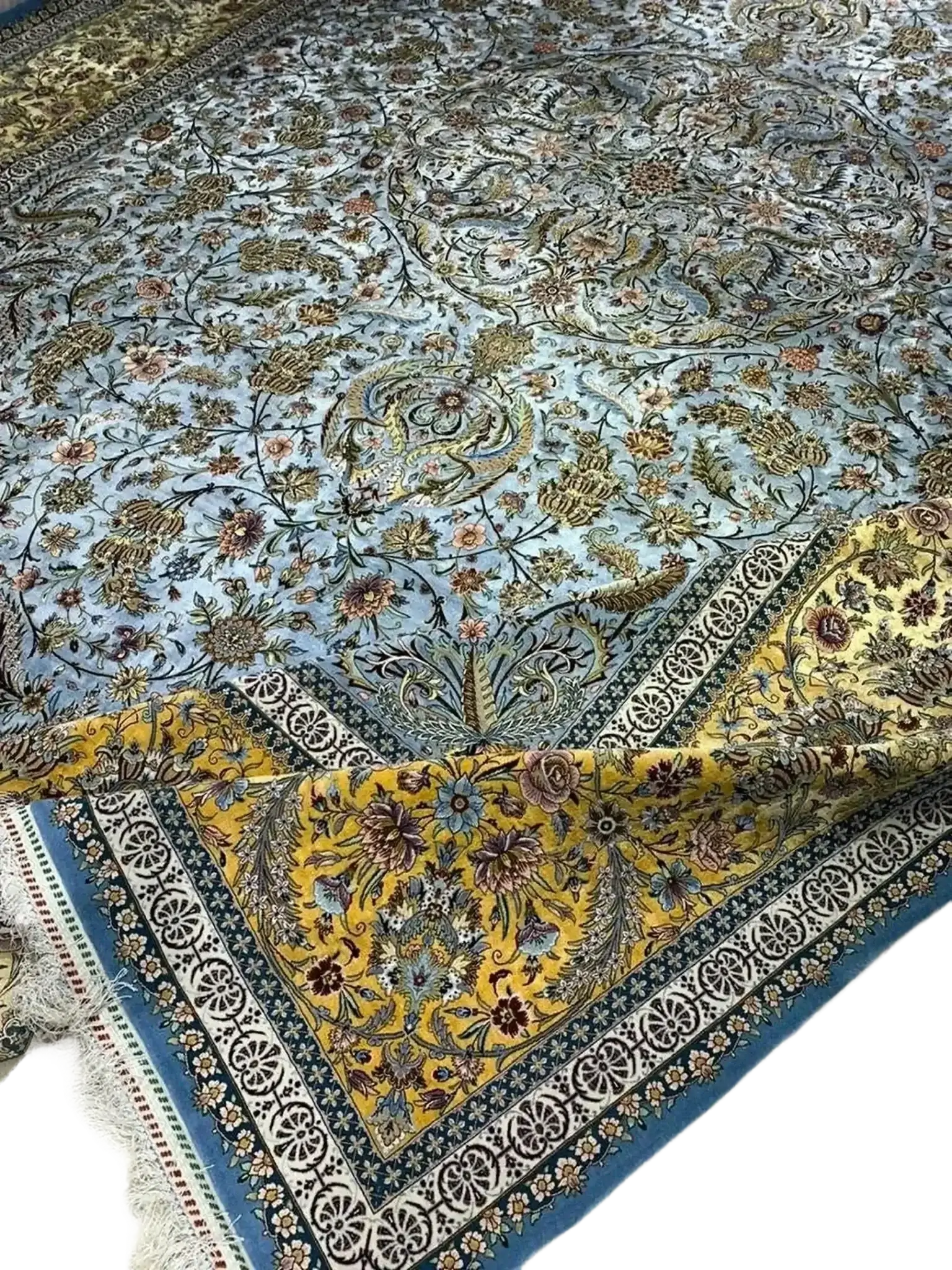 "Luxurious Persian carpet in delicate shades of blue and gold, crafted by master weavers with intricate floral designs from Isfahan, Iran."